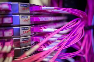 Glasfaserkabel an Netzwerkkomponenten in unserem Rechenzentrum, sauber organisiert in mehreren Serverracks