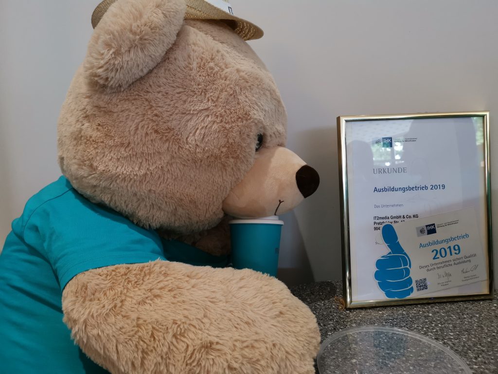 Ein Stoffbär mit einem IT2media T Shirt und einer Urkunde von der IHK