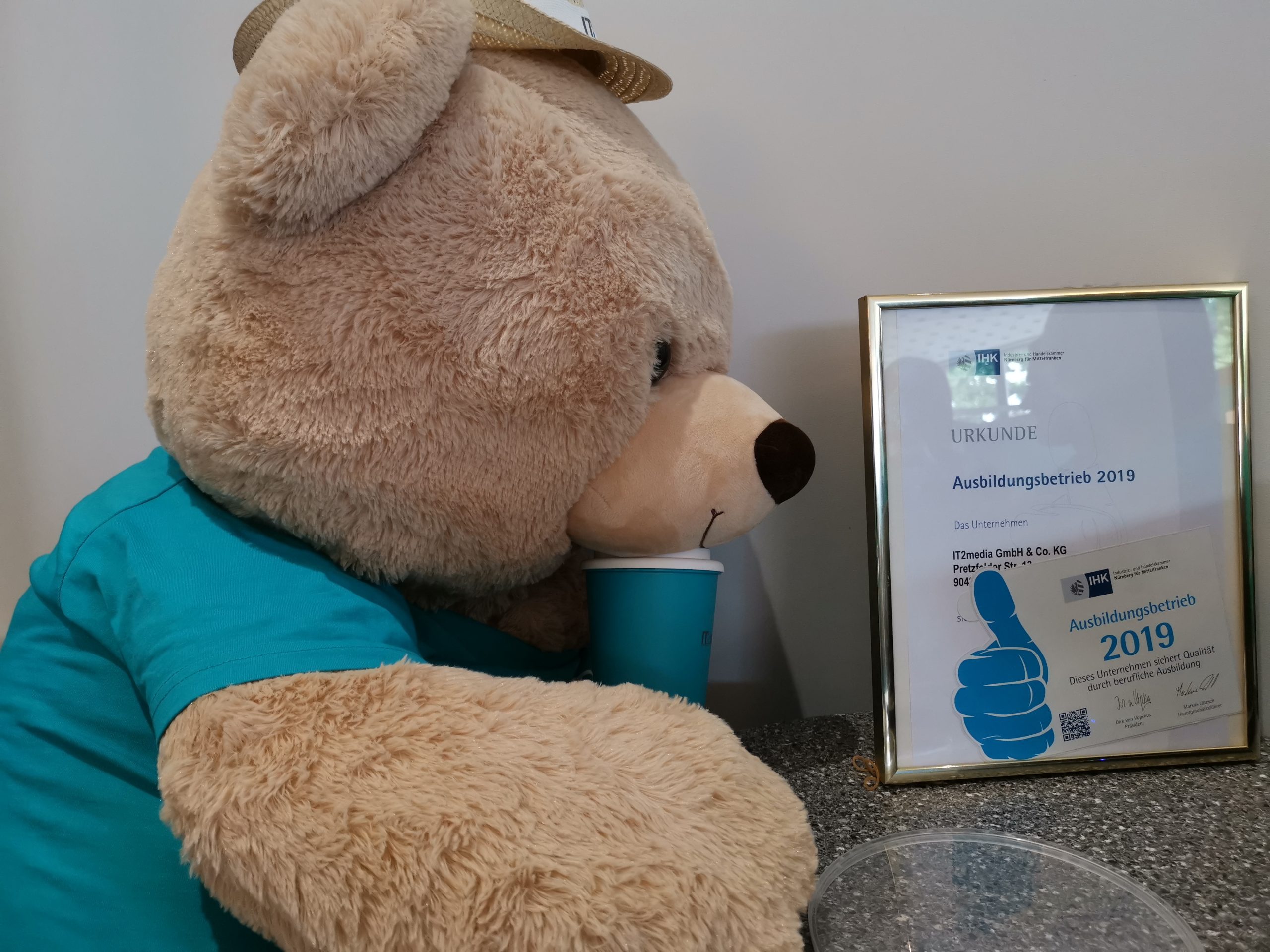 Ein Stoffbär mit einem IT2media T Shirt und einer Urkunde von der IHK